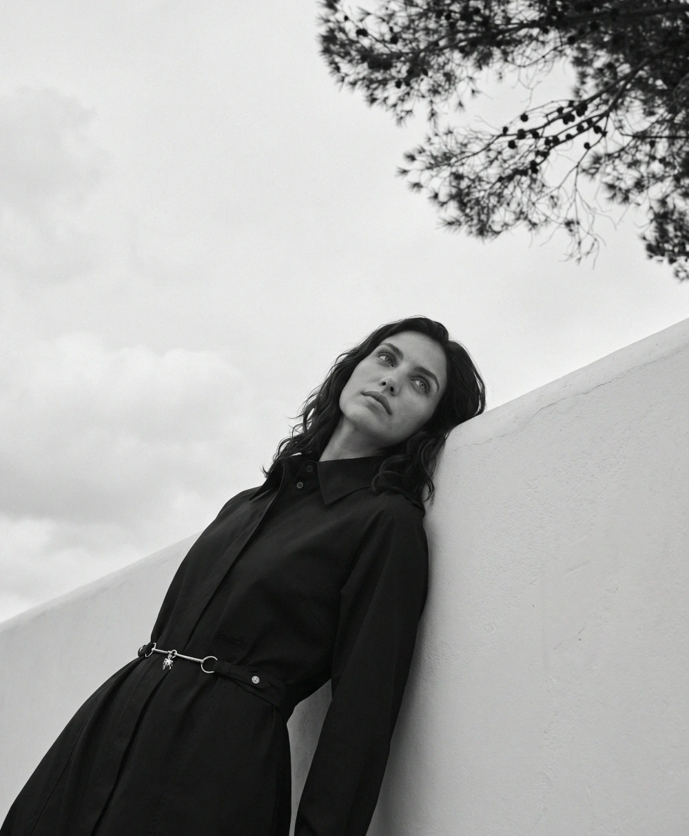 Woman leaning against a sunlit stucco wall.