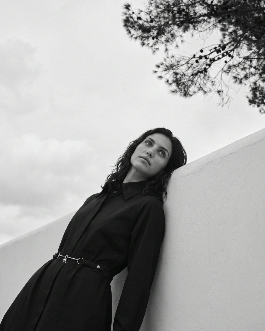 Woman against a sunlit wall, portrait crop.